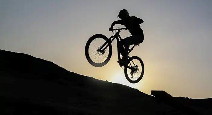 Cyclist riding through the desert landscape at Alula Bike Park, with panoramic views of rocky formations and vast terrain.