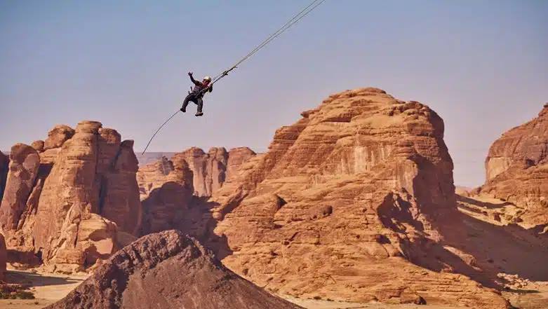 Participant experiencing the thrill of the Giant Swing at AlUla Adventure Hub with breathtaking views of the Saudi Arabian desert.