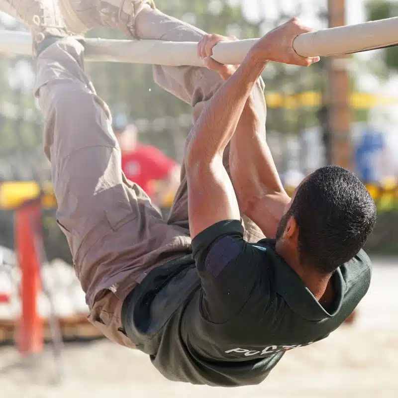 SWAT team member maneuvering through a monkey bar obstacle during the UAE SWAT Challenge, showcasing strength and coordination.