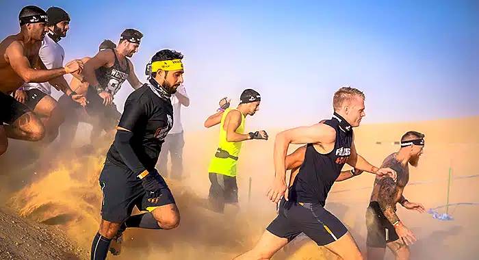 Participants running through a desert terrain during the Desert Warrior Challenge, showcasing endurance and adventure