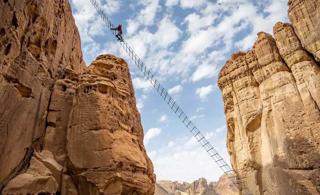 Adventure seekers climbing the Stairway at AlUla Adventure Hub, enjoying breathtaking views of the Saudi Arabian desert cliffs