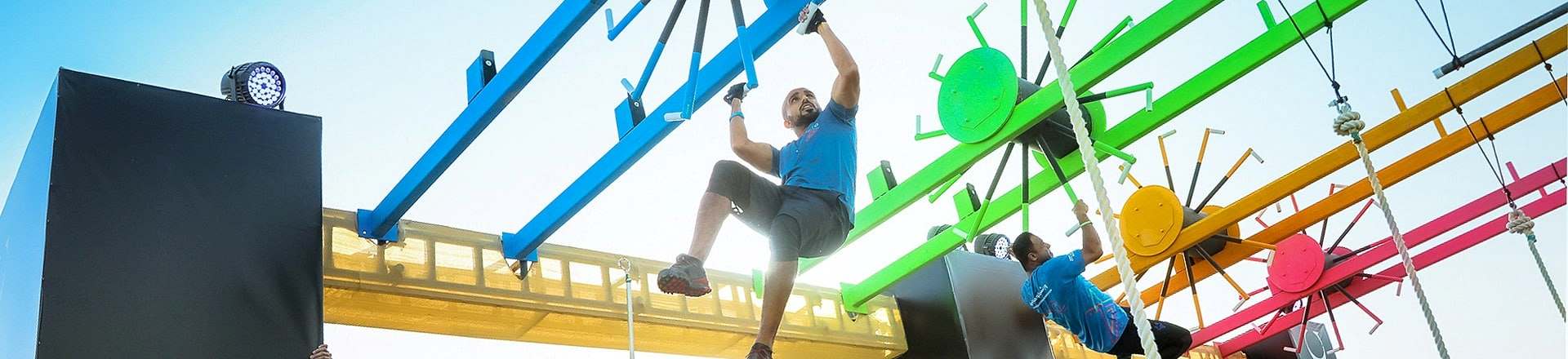 Participants competing in a challenging team obstacle event during the Government Games at Kite Beach, Dubai, showcasing teamwork and endurance.