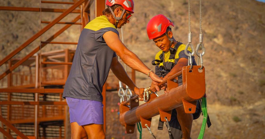 Workers inspecting a giant swing steel structure at an adventure park to ensure safety and secure operation.